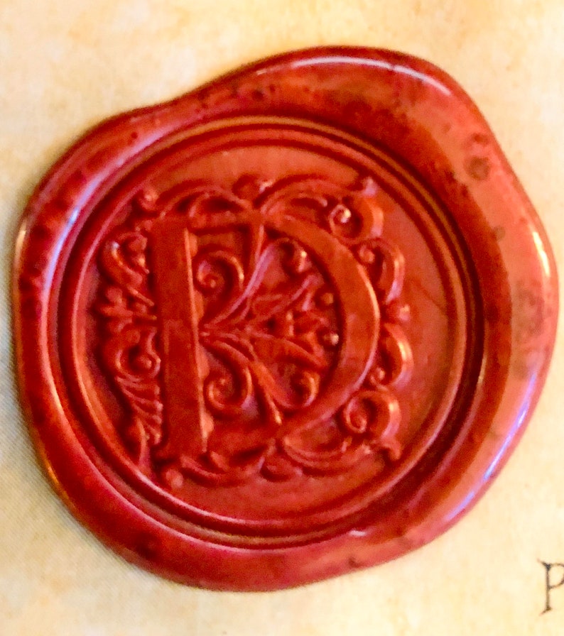 May include: A red wax seal with a decorative letter "D" in the center.
