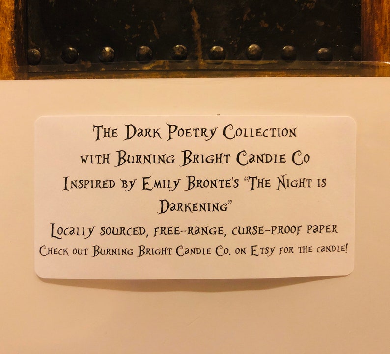 Op de afbeelding: Een witte kaart met zwarte tekst die "The Dark Poetry Collection with Burning Bright Candle Co. Inspired by Emily Bronte's "The Night is Darkening." Locally sourced, free-range, curse-proof paper. Check out Burning Bright Candle Co. on Etsy for the candle!" aankondigt.
