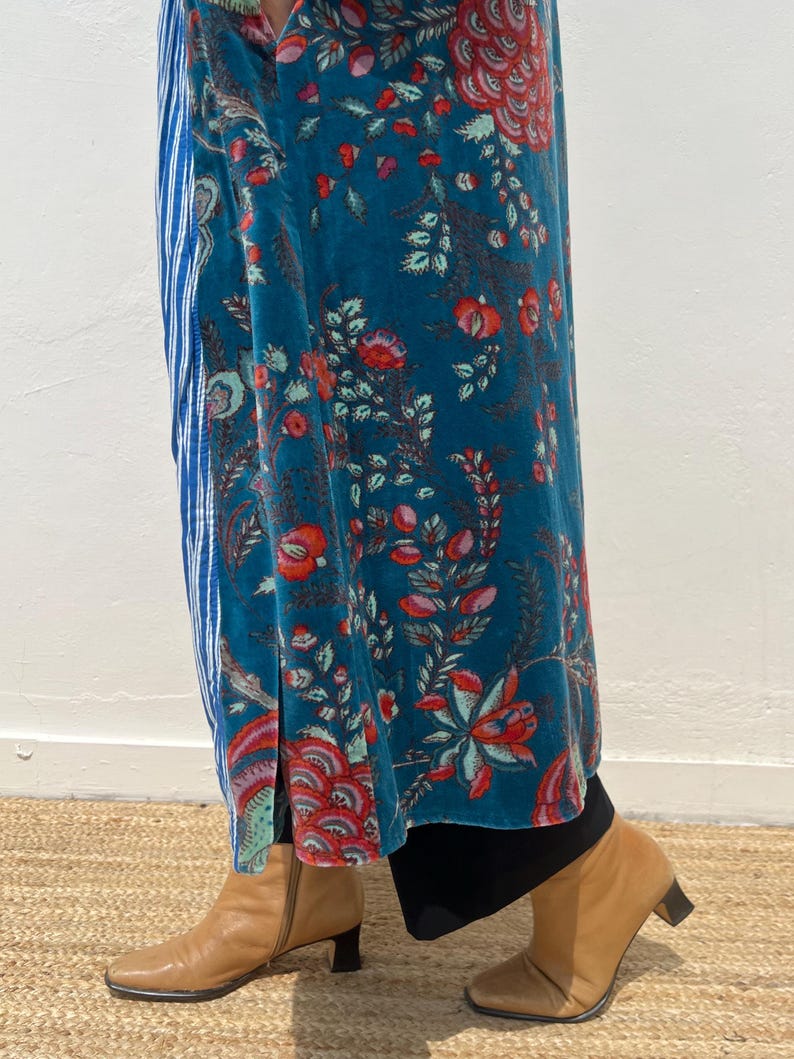 May include: A teal velvet maxi skirt with a floral pattern in red and pink, paired with a blue and white striped panel. The outfit is completed with tan leather ankle boots with a small heel.