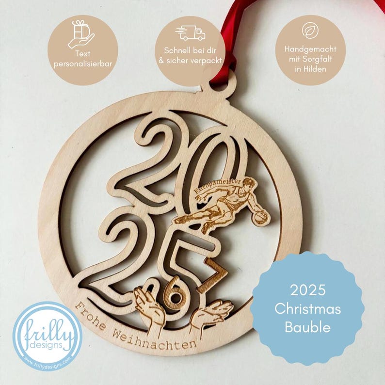Op de afbeelding: Een houten kerstbal met het jaar 2025 uitgesneden, met een basketballer en de woorden "Frohe Weihnachten". De bal heeft een rood lint om op te hangen en de tekst "2025 Christmas Bauble".