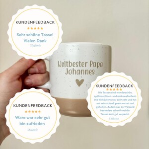May include: A white ceramic mug with a speckled finish and a solid tan base. The text 'Weltbester Papa Johannes' is printed in a dark font above a small heart icon. Three circular customer feedback badges with five-star ratings are overlaid.