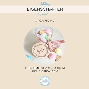 May include: A wooden round box with a lid featuring the name "Arvie" engraved on it. The box is 10 cm in diameter and 12 cm tall. The box is filled with pastel-colored candy and a pink ribbon.