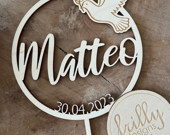 Könnte beinhalten: Holzkuchentopper mit einem runden Design mit dem Namen Matteo und dem Datum 30.04.2023. Eine Taube mit einem Olivenzweig befindet sich im Kreis. Der Topper ist auf einem Holzstiel. Ein rundes Holzschild mit dem Text "frilly designs" befindet sich in der unteren rechten Ecke.