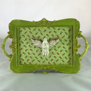 May include: A green tray with gold accents and a white dove cutout on a green and white gingham background.