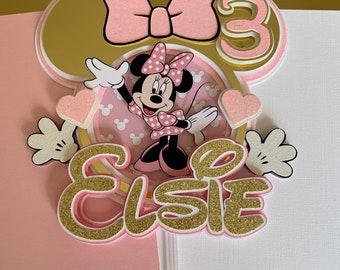 Può includere: Topper per torta a tema Minnie Mouse rosa e oro con un fiocco, il numero 3 e il nome Elsie.