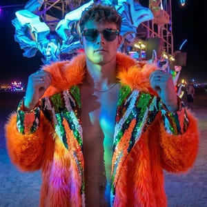 May include: A bright orange faux fur coat featuring wide lapels adorned with vertical stripes of green, white, and black sequins. The coat is worn open, revealing a bare chest, and is paired with dark-tinted aviator sunglasses with thin frames.