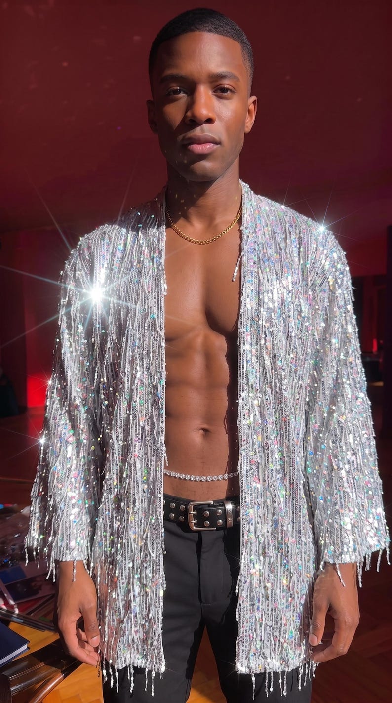 May include: A silver sequined open-front kimono-style jacket with long sleeves and a fringe-like texture. The garment is covered in reflective, shimmering sequins that catch the light, creating a metallic, high-shine appearance throughout.