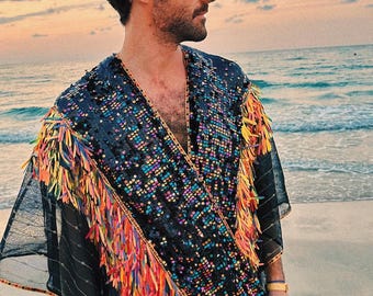 Könnte beinhalten: Eine Person trägt einen schwarzen, mit Pailletten besetzten Kimono mit bunten Akzenten. Der Kimono wird über einem weißen Hemd getragen und die Person steht an einem Sandstrand.