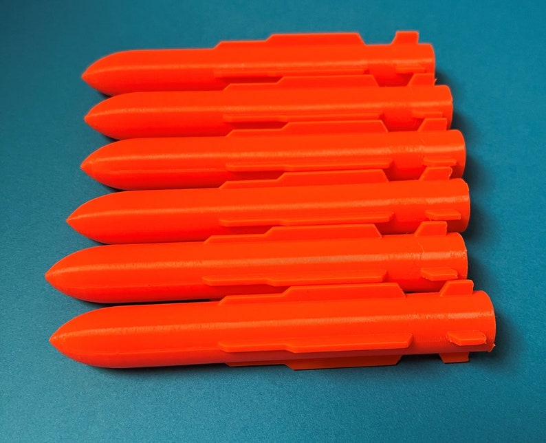 May include: A set of six orange plastic rocket-shaped objects. The objects are arranged in a row, with the tips pointing to the right.