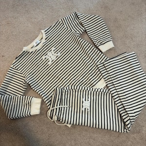 May include: A black and white striped sweater and matching pants set with a white logo on the front of the sweater.