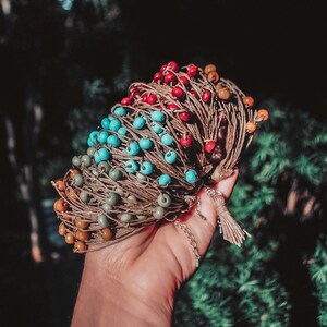May include: A stack of colorful beaded bracelets with brown string, tied together with a tassel. The bracelets are made with turquoise, red, and orange beads.