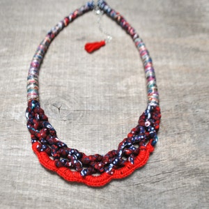 folk style print braided fabric necklace with shiny thread wrapped rope and red tassel decorated with crochet red stich