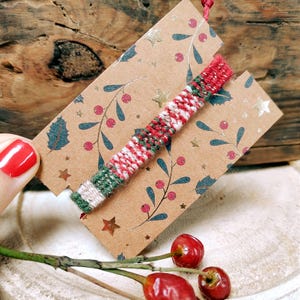 May include: A red, white, and green woven friendship bracelet with a festive Christmas theme.
