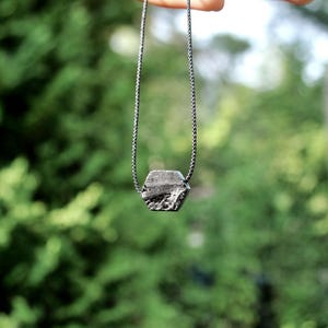 May include: A black necklace with a hexagonal black stone pendant.