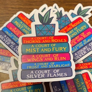 May include: A stack of five colorful stickers featuring the titles of the "A Court of Thorns and Roses" book series. The stickers are arranged in a stack, with the top sticker featuring a potted plant. The titles of the books are: "A Court of Thorns and Roses", "A Court of Mist and Fury", "A Court of Wings and Ruin", "A Court of Frost and Starlight", and "A Court of Silver Flames".