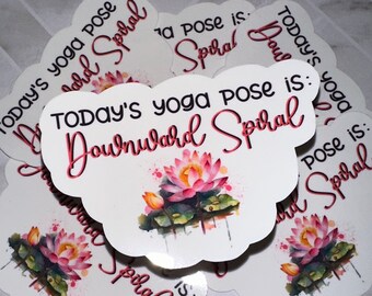 May include: White stickers with a scalloped edge, featuring the text "Today's yoga pose is: Downward Spiral" in a script font. Each sticker has a watercolor illustration of a pink lotus flower with green leaves.