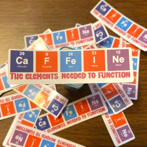 May include: A set of colorful square stickers with the chemical symbols and names of the elements Calcium, Fluorine, Iron, Iodine, and Neon. The stickers are arranged in a row with the text "The Elements Needed to Function" printed below them.