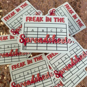 May include: A set of six white stickers with a black grid and the text "Freak in the Spreadsheets" in red and black. The stickers are designed to look like a spreadsheet.