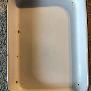 May include: White enamel baking dish with a black rim. The dish has some rust spots on the rim.