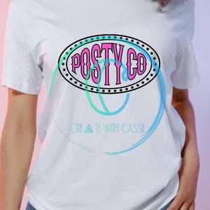 Może przedstawiać: Biała koszulka z różowo-niebieskim owalnym wzorem. Tekst "POSTY CO" jest w stylizowanej czcionce, otoczony kropkowaną obwódką. Poniżej wzoru znajduje się tekst "CREATE WITH CASSIE" w kolorze turkusowym.