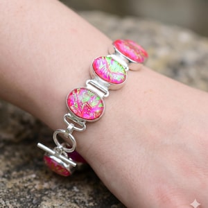 Peut inclure: Un bracelet à maillons en argent composé de plusieurs cabochons ovales arborant un motif marbré rose vif et vert citron irisé. Le bracelet est doté d'un fermoir à bascule et comprend une breloque ovale assortie fixée à la fermeture.
