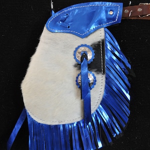 May include: Blue and white leather chaps with fringe and silver conchos. The chaps are made of cowhide and have a blue metallic fringe.