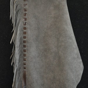 May include: Gray suede chaps with brown leather fringe and a brown leather top with a woven design.