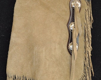May include: Tan leather chaps with fringe and a brown leather top with a woven design. The chaps have silver conchos and tassels.