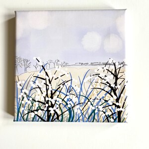 May include: A square canvas art print featuring a serene landscape. The artwork depicts stylized trees, tall grass, and white flowers against a soft blue sky. The color palette includes blue, green, white, and beige.
