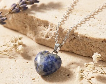 May include: A heart-shaped blue and grey stone pendant hangs from a delicate silver-toned metal chain. The pendant features a smooth, polished surface with natural mottled patterns, suspended by a simple metal bail attached to the chain links.