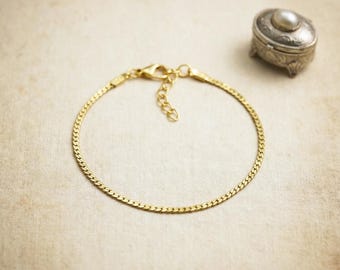 May include: A delicate gold-colored bracelet with a chain-like design. The bracelet is shown on a neutral background, with a small, ornate silver box with a pearl on top in the background. The bracelet is approximately 7 inches in length.