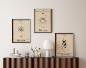 May include: Three black framed prints with beige backgrounds and black illustrations of the Sun, Moon, and Star. The prints are labeled with Roman numerals and the names of the celestial bodies. The prints are hanging on a white wall above a wooden shelf.