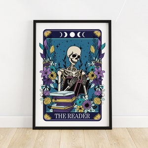 May include: A tarot card illustration featuring a skeleton reading a book. The card is surrounded by flowers and has a blue background with stars and moons. The text "THE READER" is at the bottom of the card.
