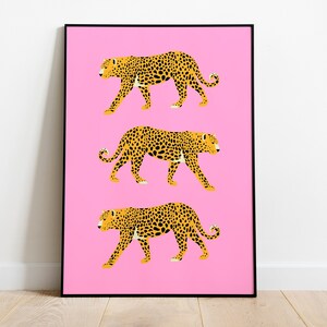 Op de afbeelding: Drie gele en zwarte luipaardprint illustraties op een roze achtergrond. De luipaarden lopen in een rij, met hun gezicht naar de rechterkant van de afbeelding.