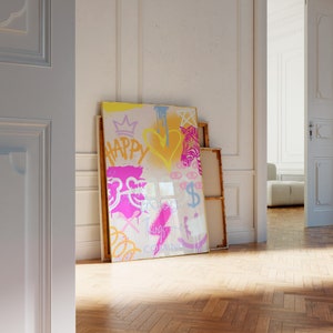 K&ouml;nnte beinhalten: Ein farbenfrohes abstraktes Gem&auml;lde mit Graffiti-Schriftzug, darunter die W&ouml;rter "Happy" und "Things are Coming". Das Gem&auml;lde ist in Gold gerahmt und lehnt an einer wei&szlig;en Wand.
