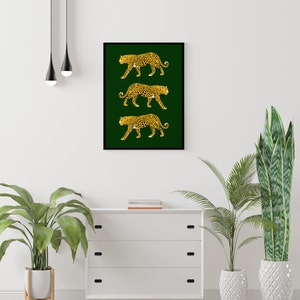 May include: A framed print with three gold leopards walking on a dark green background.