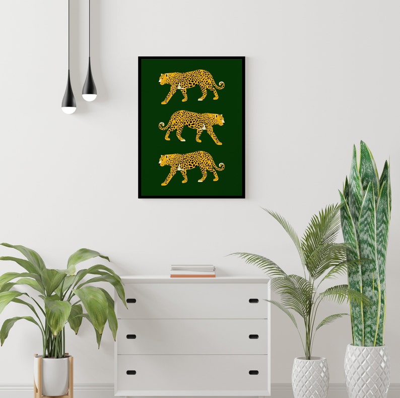 May include: A framed print with three gold leopards walking on a dark green background.