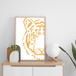 Puede incluir: Una impresi&oacute;n enmarcada de la cara de un tigre en un estilo minimalista. El tigre est&aacute; delineado en naranja sobre un fondo blanco.