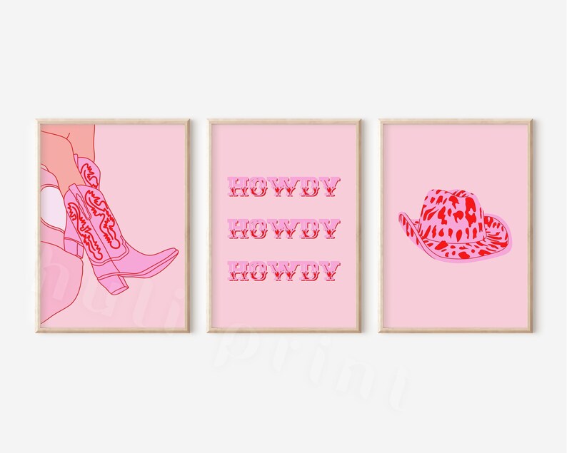 Op de afbeelding: Drie roze en rode printbare wandkunstprints. De eerste print toont een paar roze cowboylaarzen met rode stiksels. De tweede print heeft het woord "HOWDY" drie keer herhaald in het rood. De derde print toont een roze cowboyhoed met een rode luipaardprint.