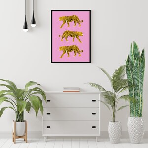 Op de afbeelding: Een roze achtergrond met drie zwarte en gele luipaardprint illustraties die in een rij lopen.