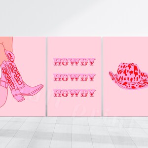 Op de afbeelding: Drie roze en rode printbare wandkunstprints. De eerste print toont een roze cowboylaars met rode stiksels. De tweede print heeft het woord "Howdy" drie keer herhaald in het rood. De derde print toont een roze cowboyhoed met een rode en roze luipaardprint.