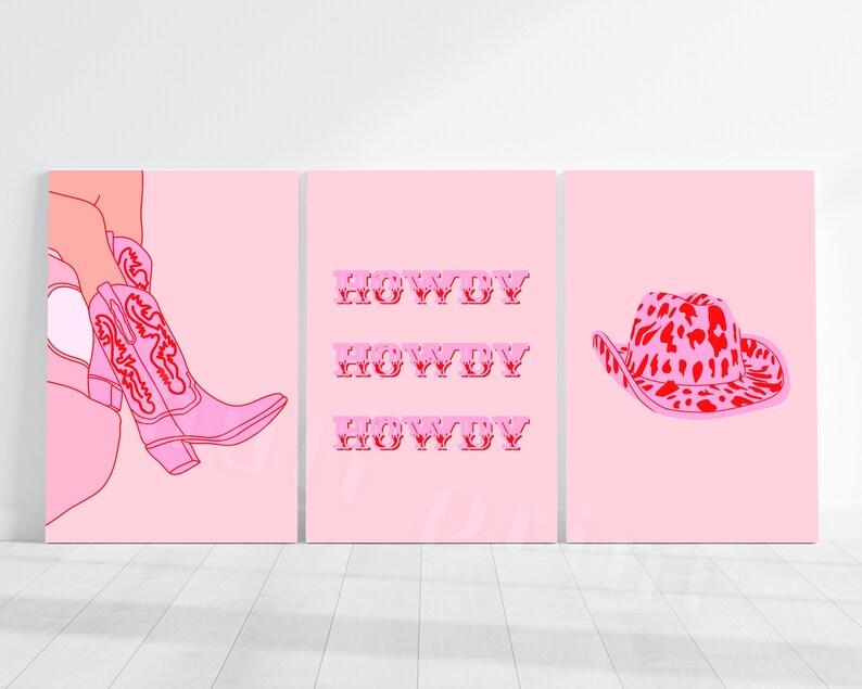 Op de afbeelding: Drie roze en rode printbare wandkunstprints. De eerste print toont een roze cowboylaars met rode stiksels. De tweede print heeft het woord "Howdy" drie keer herhaald in het rood. De derde print toont een roze cowboyhoed met een rode en roze luipaardprint.