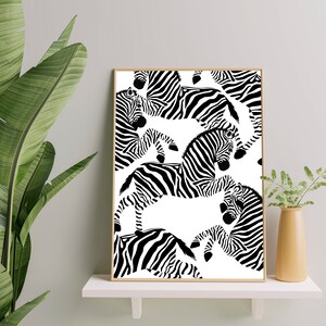 May include: Black and white print of a repeating pattern of zebras on a white background. The zebras are in various positions, some are facing the viewer, some are facing away, and some are in profile. The print is framed in a light wood frame.