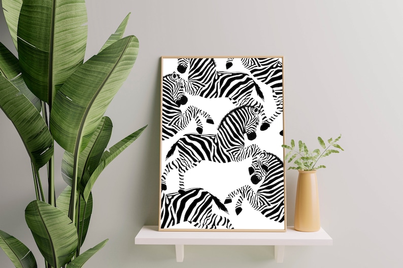 May include: Black and white print of a repeating pattern of zebras on a white background. The zebras are in various positions, some are facing the viewer, some are facing away, and some are in profile. The print is framed in a light wood frame.