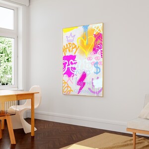 K&ouml;nnte beinhalten: Ein farbenfrohes abstraktes Gem&auml;lde mit wei&szlig;em Hintergrund und goldenem Rahmen. Das Gem&auml;lde zeigt verschiedene Formen, darunter Herzen, Sterne und Augen. Der Text "Happy Things Are Coming" ist in rosa und lila Buchstaben geschrieben.
