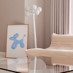 May include: A light blue balloon animal shaped like a dog in a framed print on a white wall with a white floor lamp with white globe lights and a light beige sofa in the background.