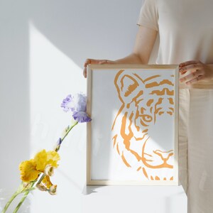 Puede incluir: Una impresi&oacute;n enmarcada de la cara de un tigre en naranja sobre un fondo blanco. La cara del tigre est&aacute; estilizada y tiene un dise&ntilde;o simple.