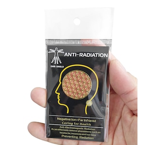 Peut inclure: Un autocollant anti-radiation noir et doré dans un emballage plastique transparent. L'autocollant présente une silhouette humaine stylisée, le texte "ANTI-RADIATION" et un motif doré dans une silhouette de tête. Le texte "Negative Ion+Far Infrared Caring for Health" est également visible.