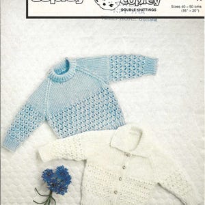 May include: A light blue and white knitted baby sweater with a textured pattern. The image also shows a white cardigan with buttons. The text on the image says "Baby Copley Double Knittings". Sizes are 16-20 inches.