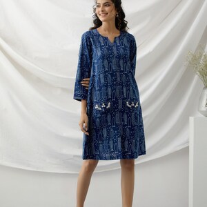 May include: A blue cotton dress with a white fish print and pearl embellishments. The dress has a v-neck and three-quarter sleeves.
